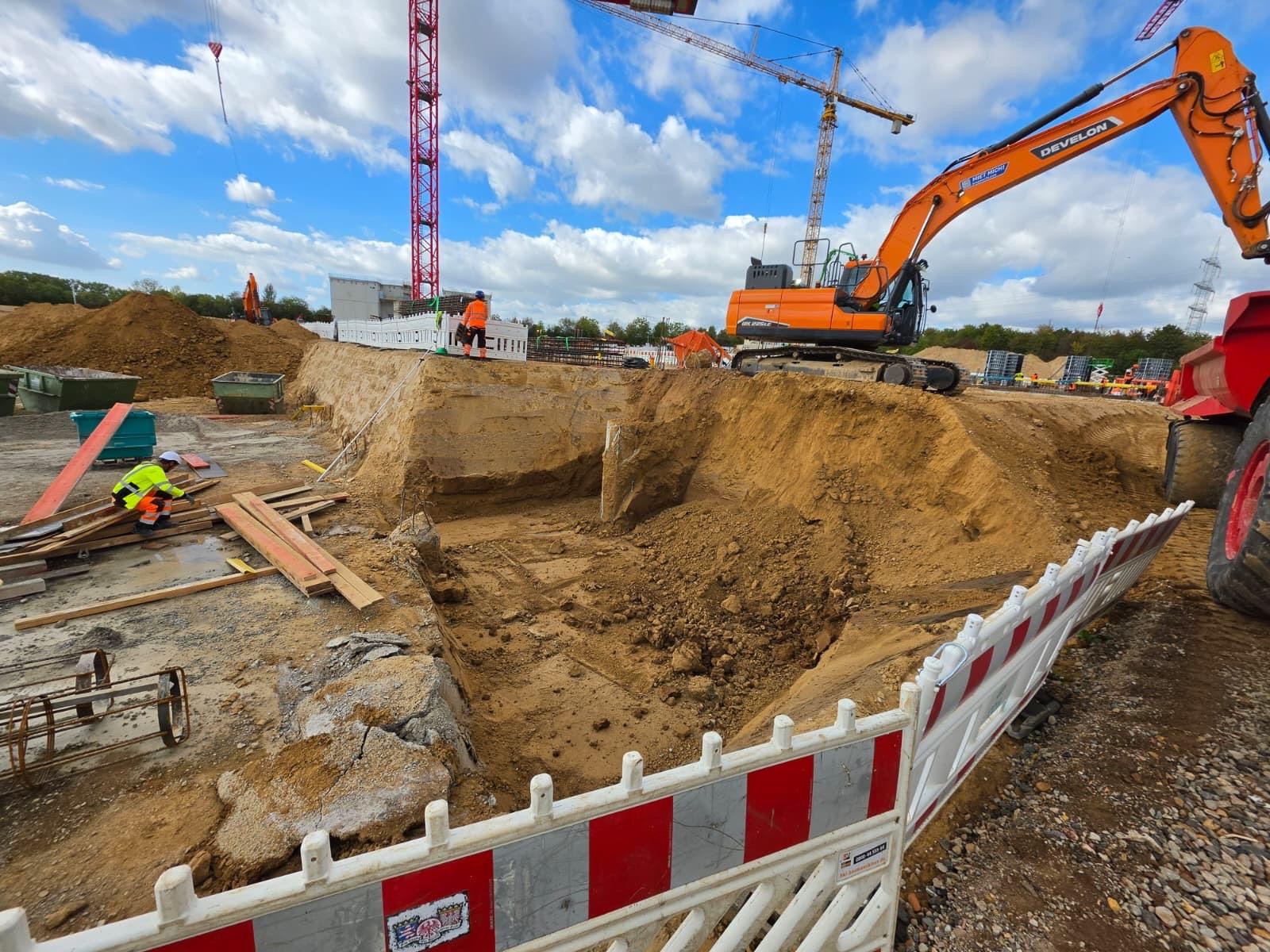 Große Baustelle mit Bagger und Kränen bei Erdarbeiten